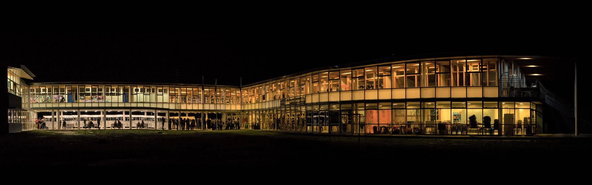 Panorámica nocturna del colegio iluminado durante un evento escolar