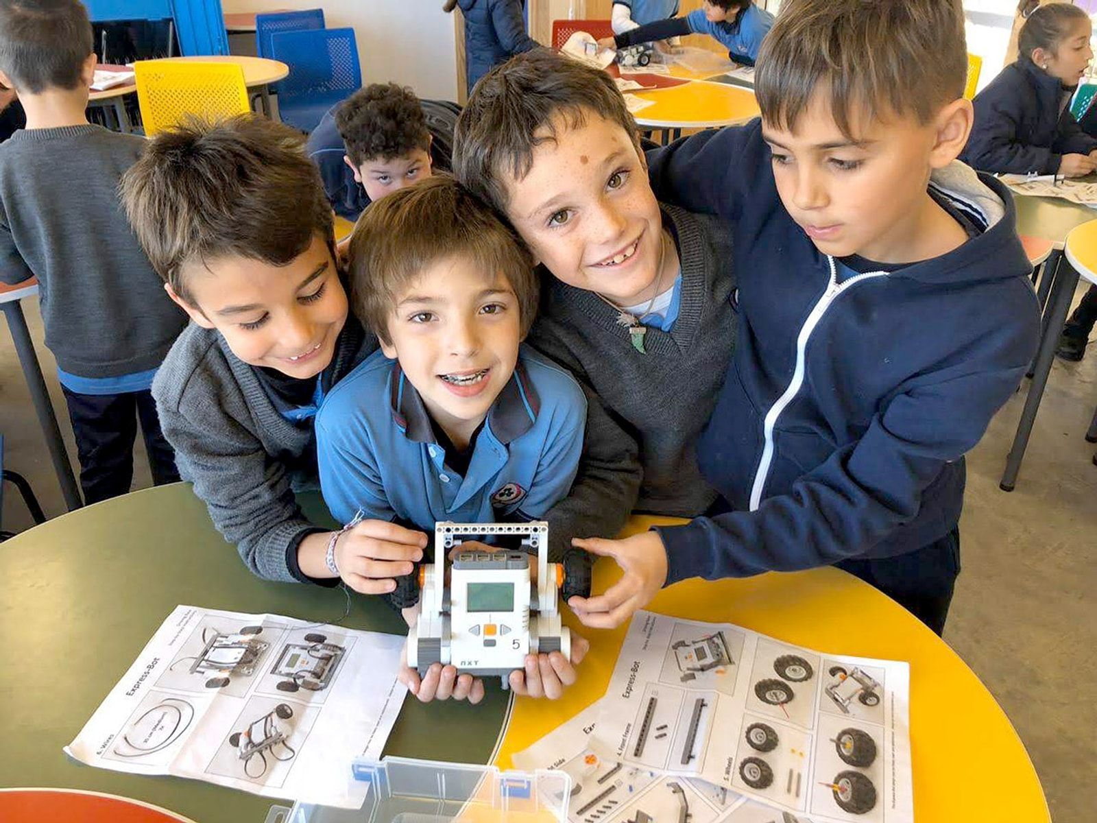 Cuatro alumnos mostrando con orgullo el robot que armaron en clase de tecnología