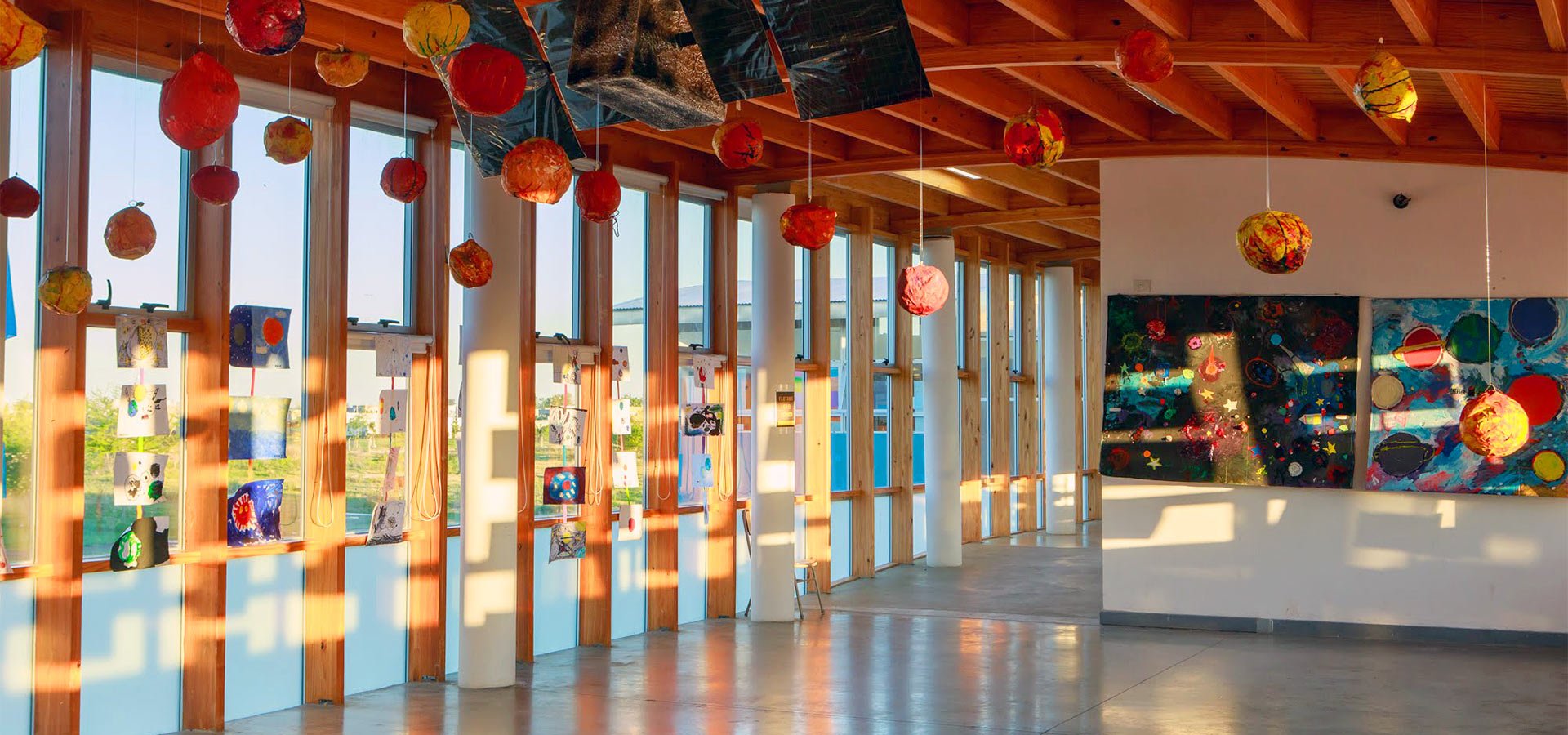 Vista panorámica del salón de arte con planetas colgantes hechos por los alumnos